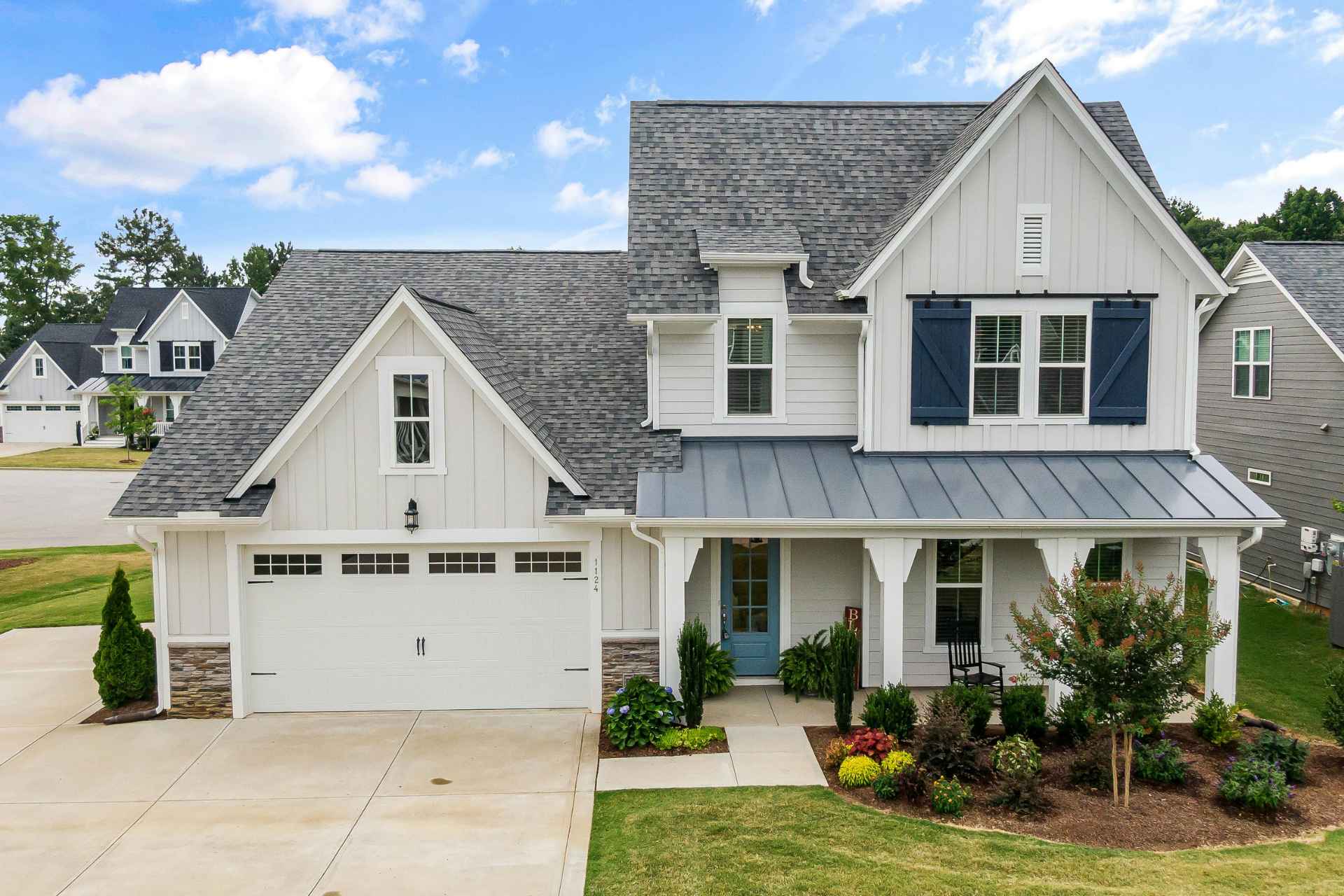 Forward-facing residential house with clean white siding and a dark gray roof during daytime.